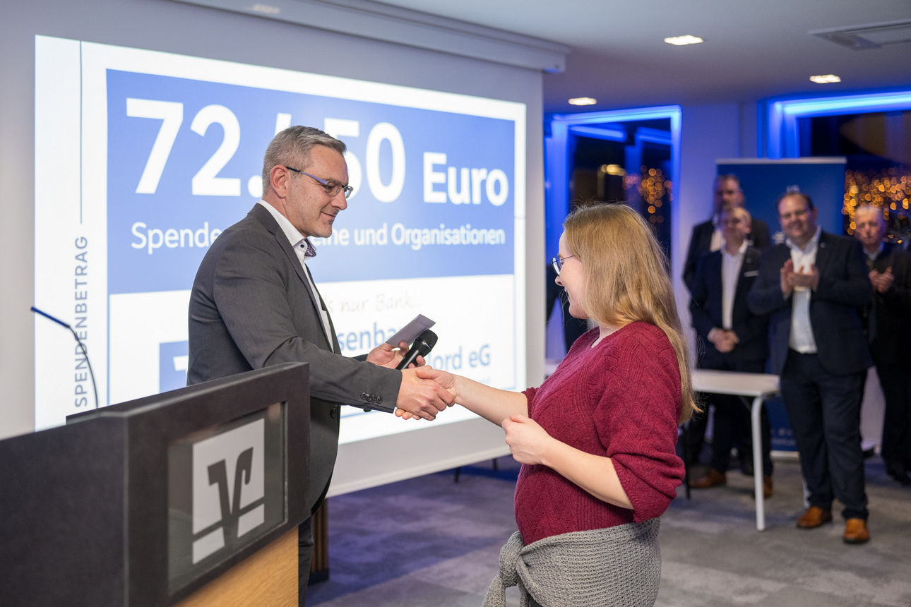 Ein Mann mit einem Mikrofon wärend er einer Frau die Hand reicht.