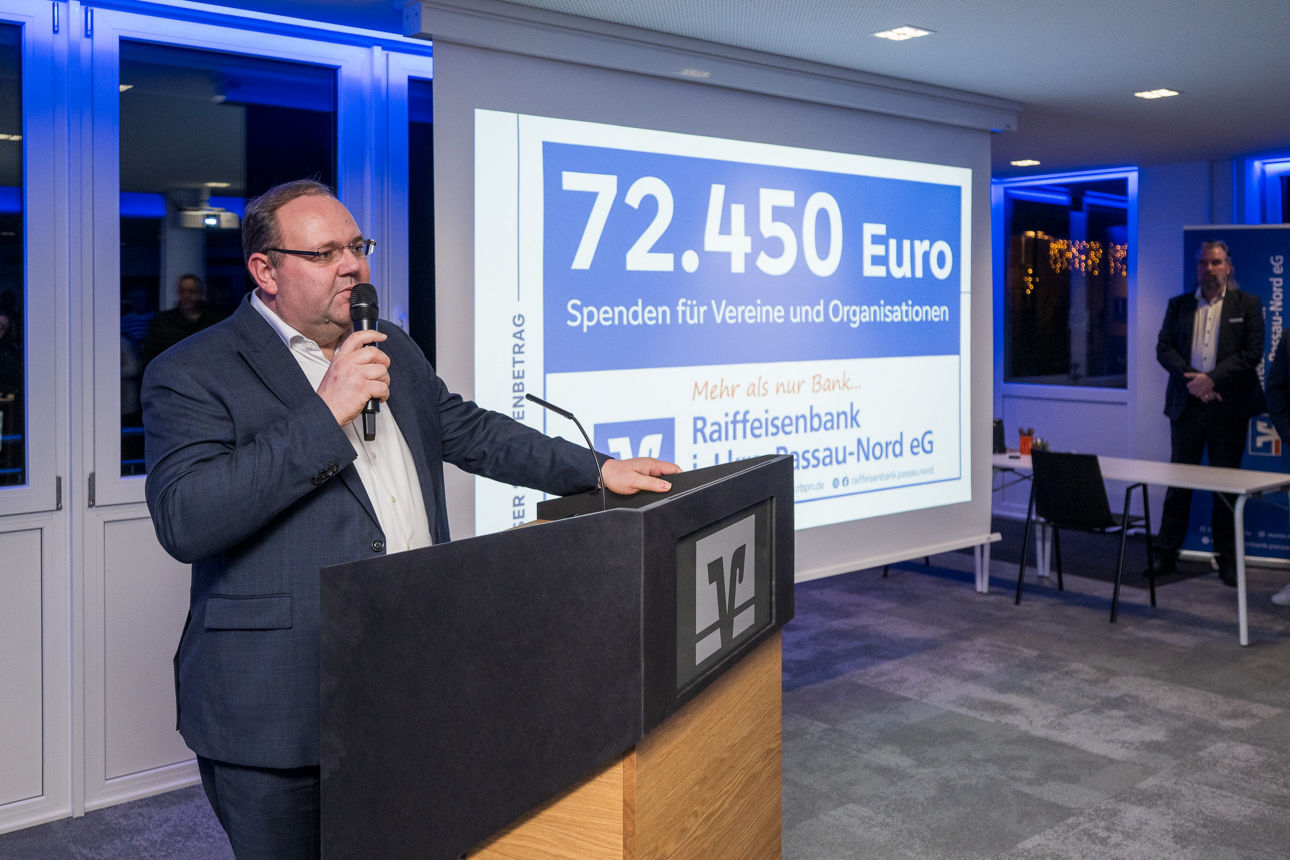 Ein Mann auf der Bühne wärend er eine Rede hält.