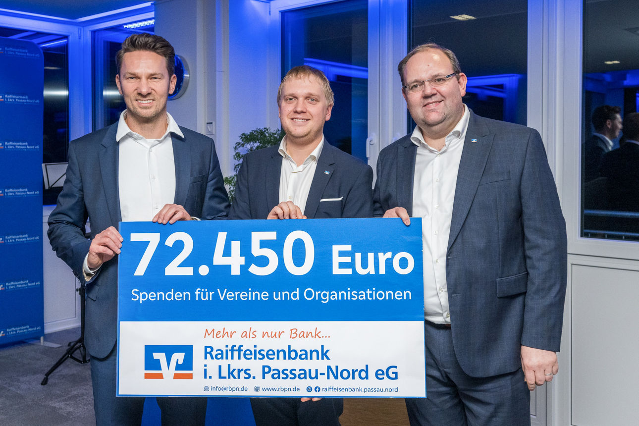 Der Scheck über 72.450 Euro und drei Herren im Hintergrund. 