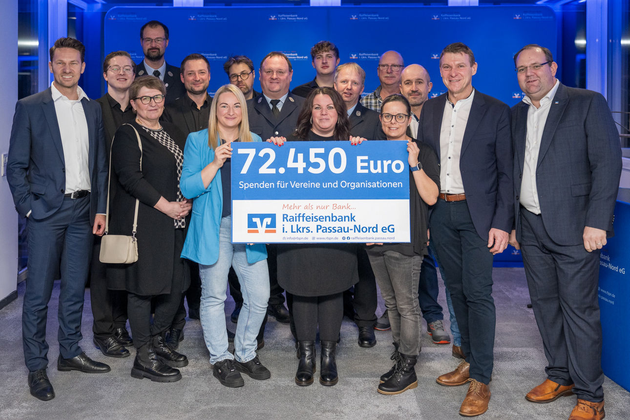 Der Scheck über 72.450 Euro und eine Gruppe von Menschen im Hintergrund. 