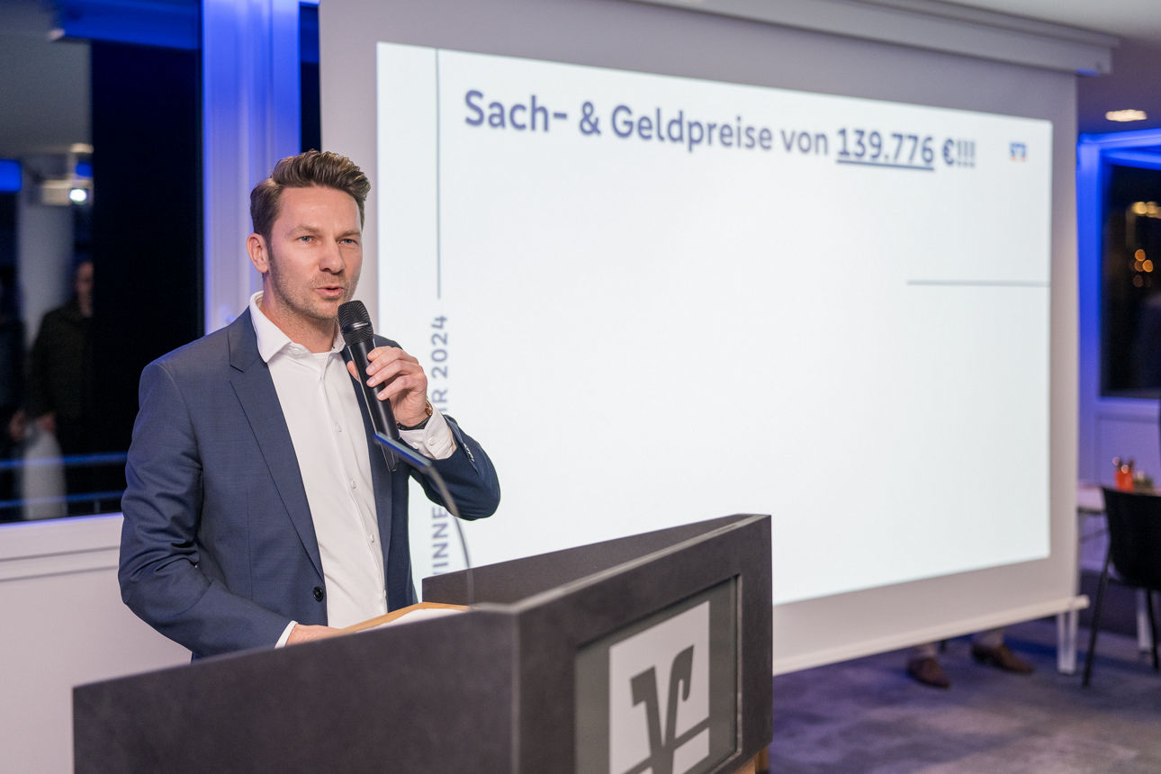 Ein Mann auf der Bühne wärend er spricht.