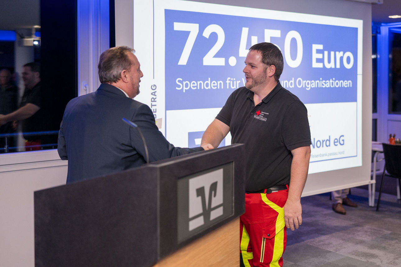 Ein Mann mit einem Mikrofon wärend er einem Mann die Hand reicht.