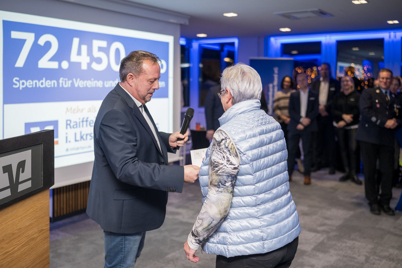 Ein Mann mit einem Mikrofon wärend er einer Frau die Hand reicht.