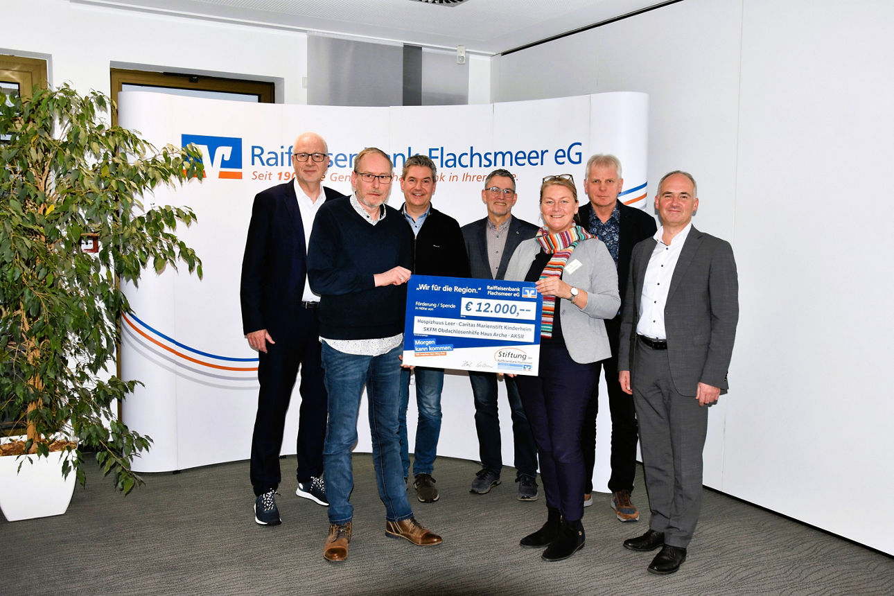 Eine Gruppe von Männern und eine Frau, die einen Preis in Höhe von 12.000 Euro in den Händen halten