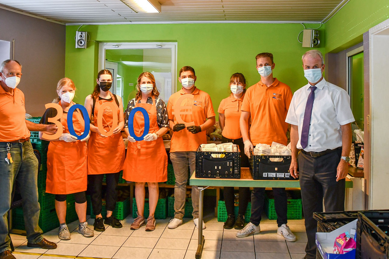 Mitarbeitende der Asbacher Tafel und der Raiffeisenbank halten mit orange-blauen Zahlen die Spendensumme von 3.000 € hoch