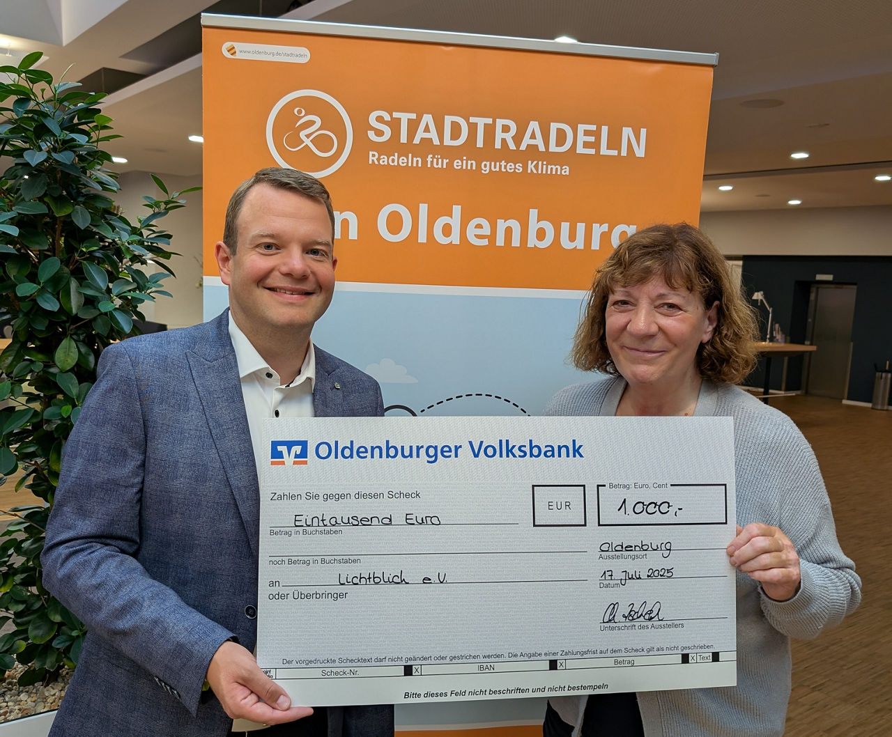 Zwei Menschen bei einer symbolischen Scheckübergabe