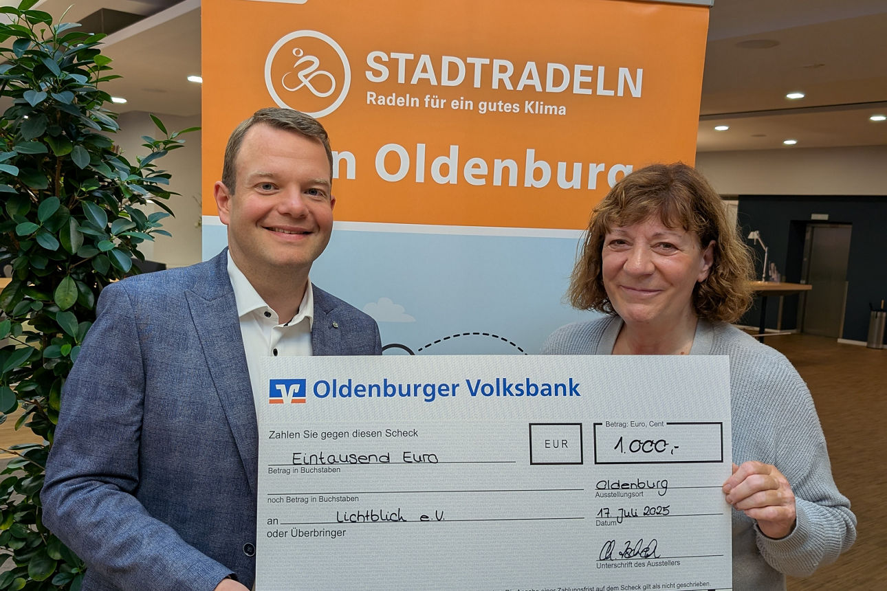 Zwei Menschen bei einer symbolischen Scheckübergabe