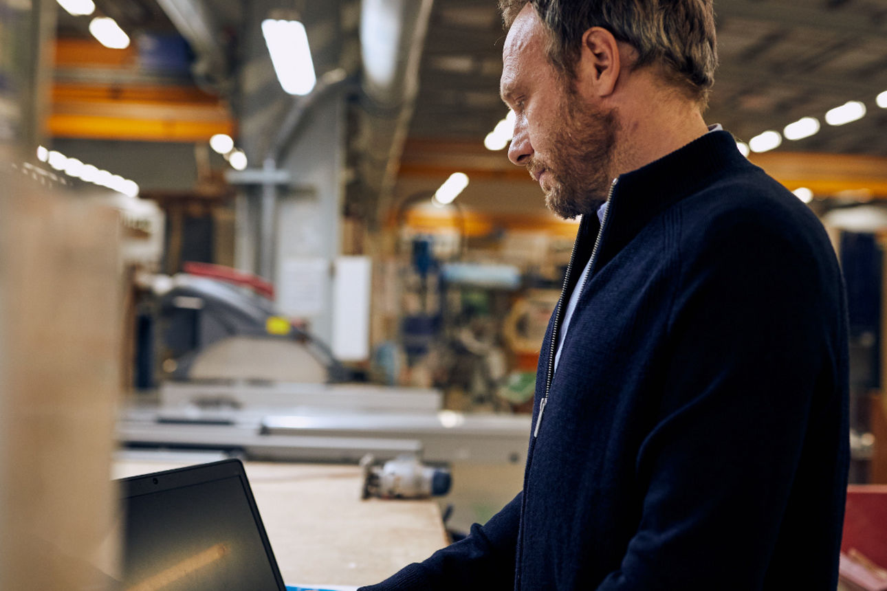 Ein Mann arbeitet in einer Werkstatt an einem Laptop.