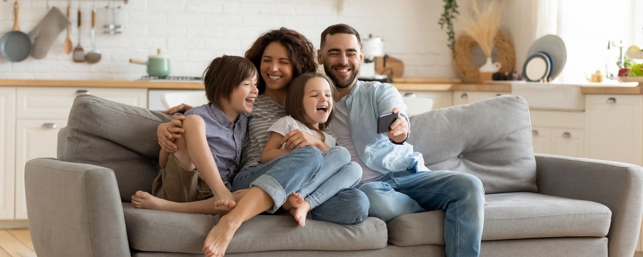 Eine Familie sitzt lächelnd auf dem Sofa