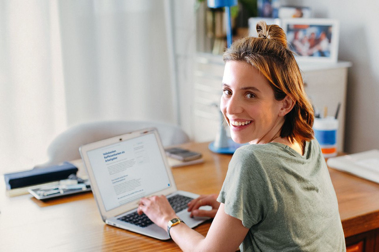 Lächlende Frau informiert sich über Stellenangebote an ihrem Laptop