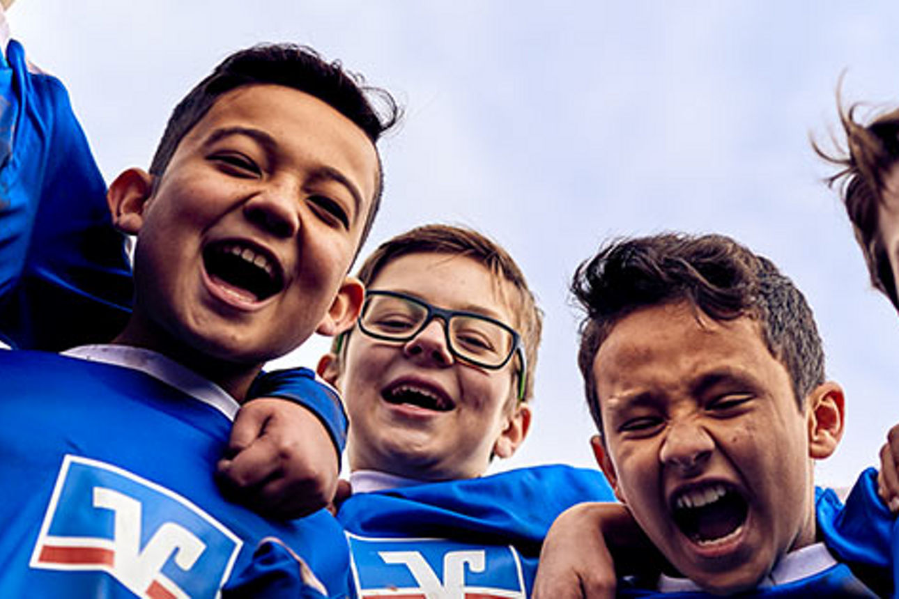 Eine Gruppe von Jungen in blauen Hemden, die lächelnd in einer fröhlichen Umgebung zusammenstehen.