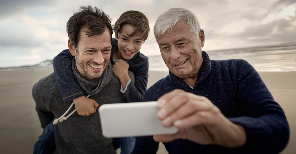 Ein Vater, ein Sohn und ein Großvater machen ein Selfie am Strand