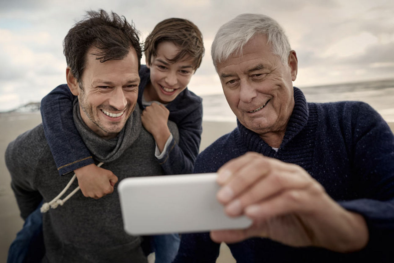 Ein Vater, ein Sohn und ein Großvater machen ein Selfie am Strand