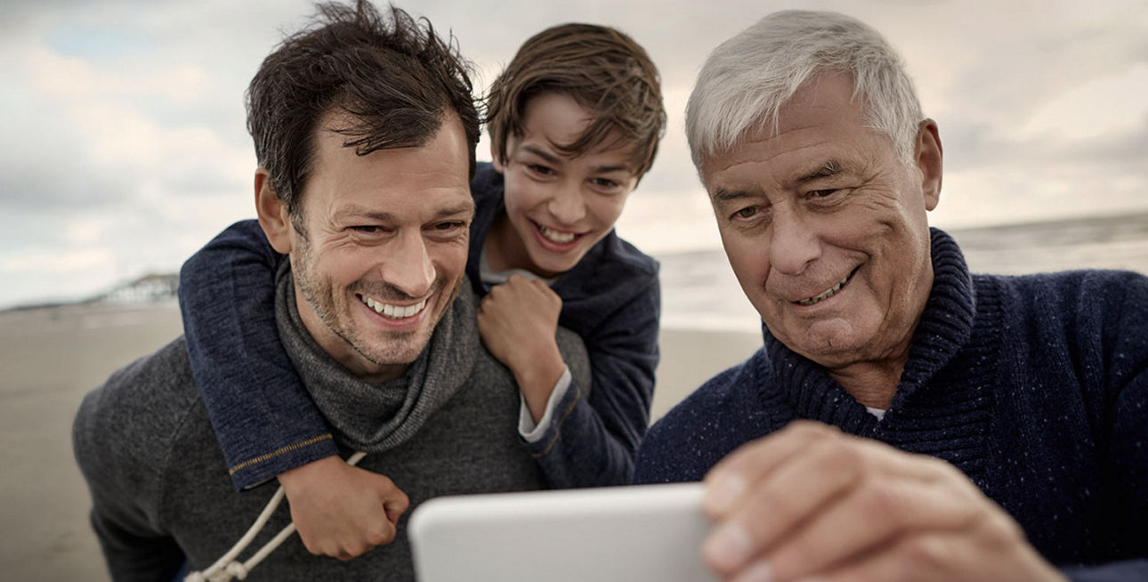 Großvater, Vater und Sohn stehen am Strand und machen ein Selfie