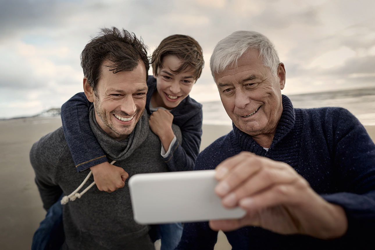 Großvater, Vater und Sohn stehen am Strand und machen ein Selfie