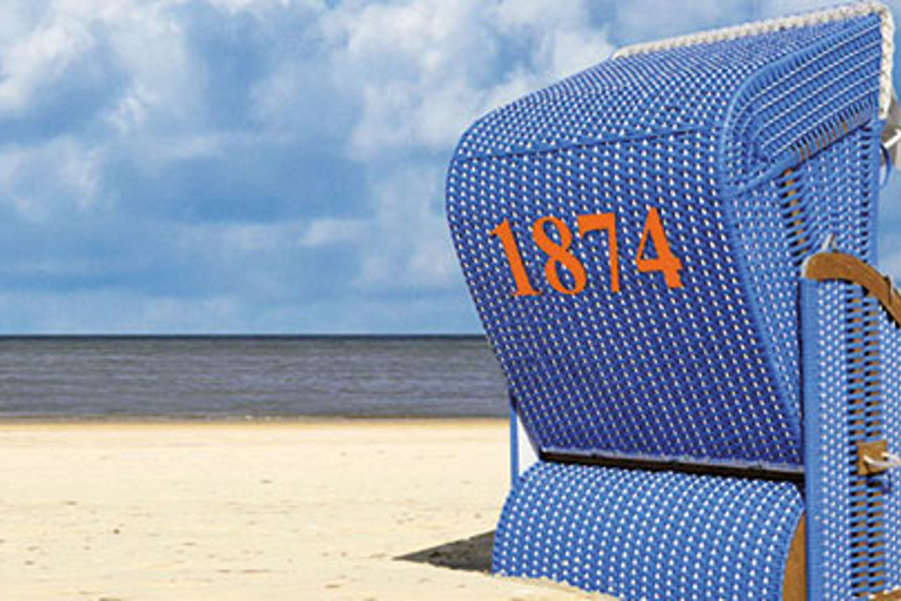 Ein blauer Strandkorb steht an einem Sandstrand mit Meerblick