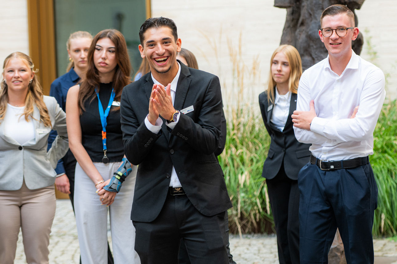 Jugendliche sitzen in einem Vortrag und werden durch eine Scheibe fotografiert