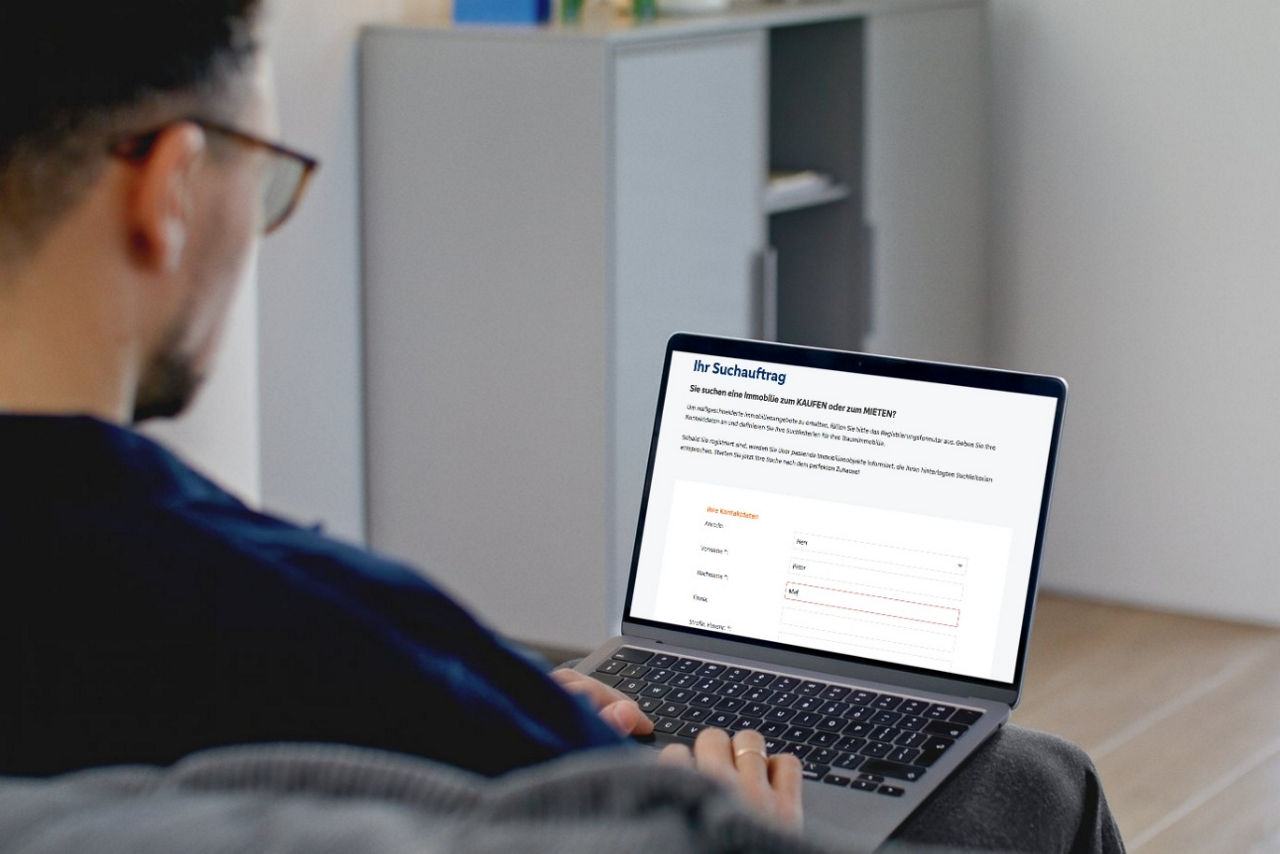 Mann am Notebook gibt einen Immobiliensuchauftrag ein.