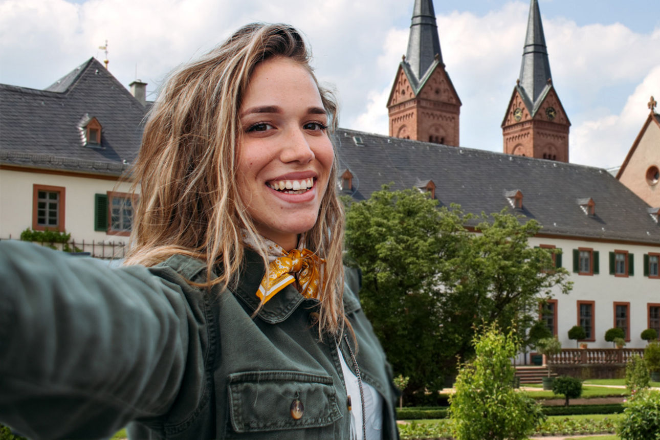 Glückliche junge Frau macht Selfie vor einer Kirche