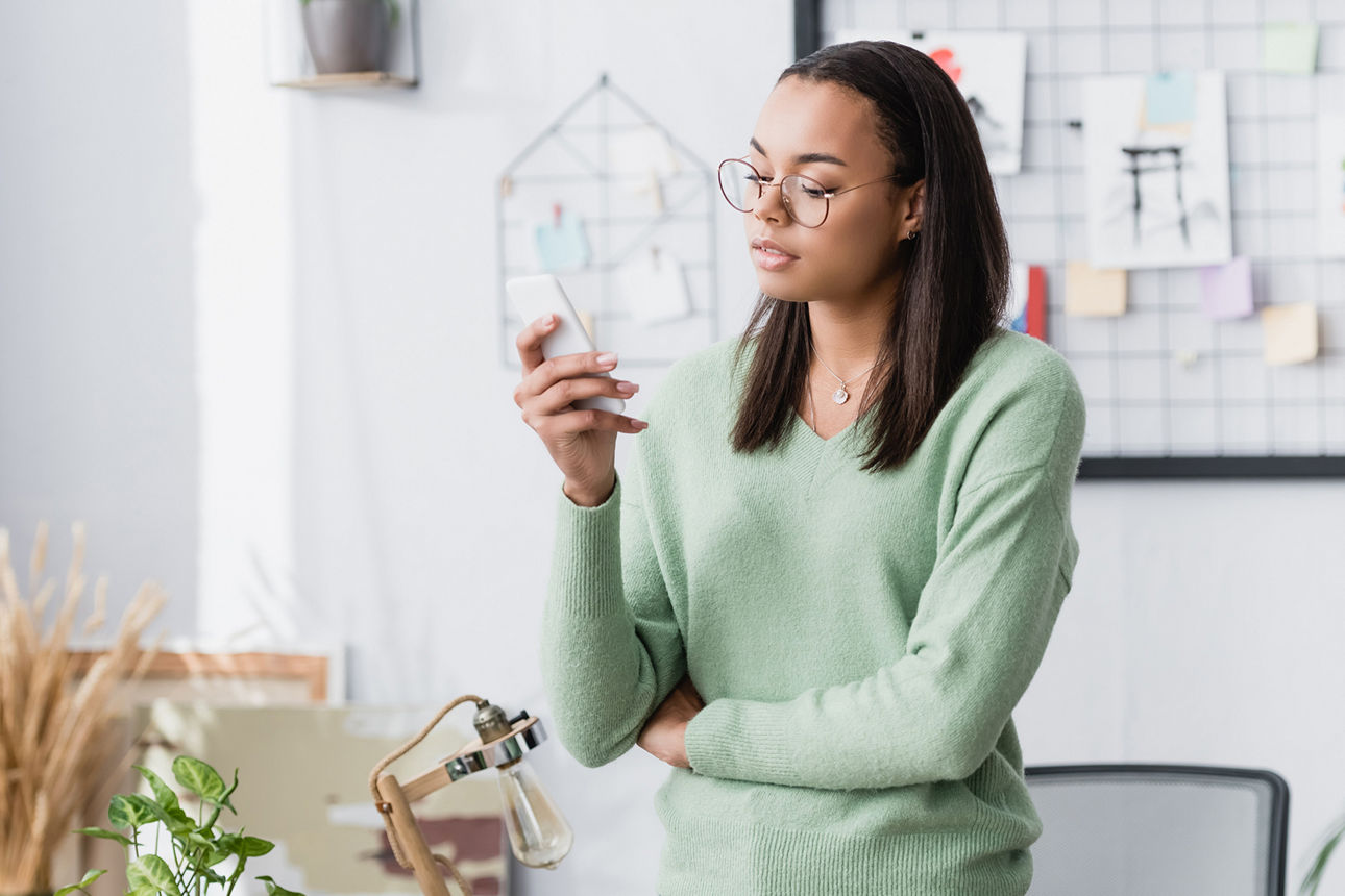 Junge Frau im Büro tippt Nachrichten auf dem Smartphone