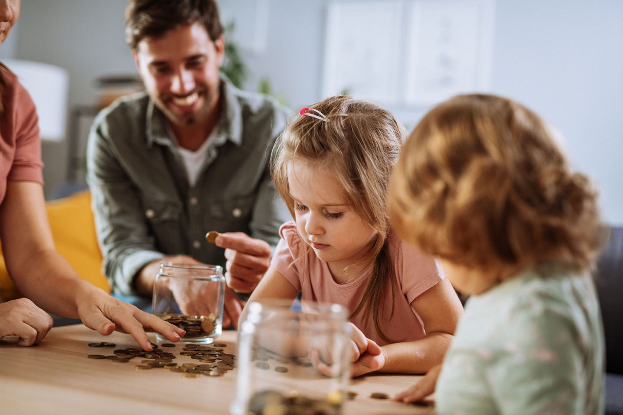 Eltern legen für ihre zwei Kinder Geld in ein Glas.