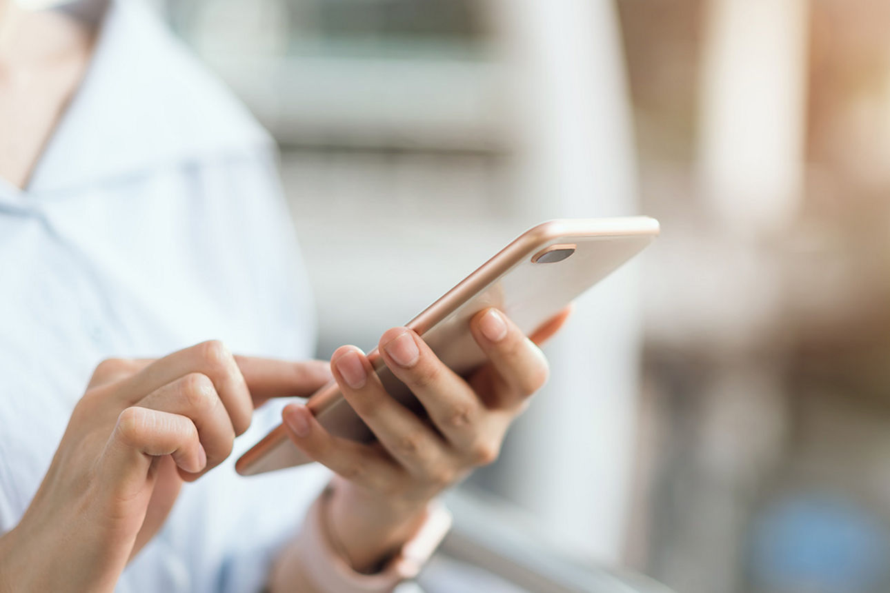 Frau die auf einem Smartphone mit dem Finger tippt.