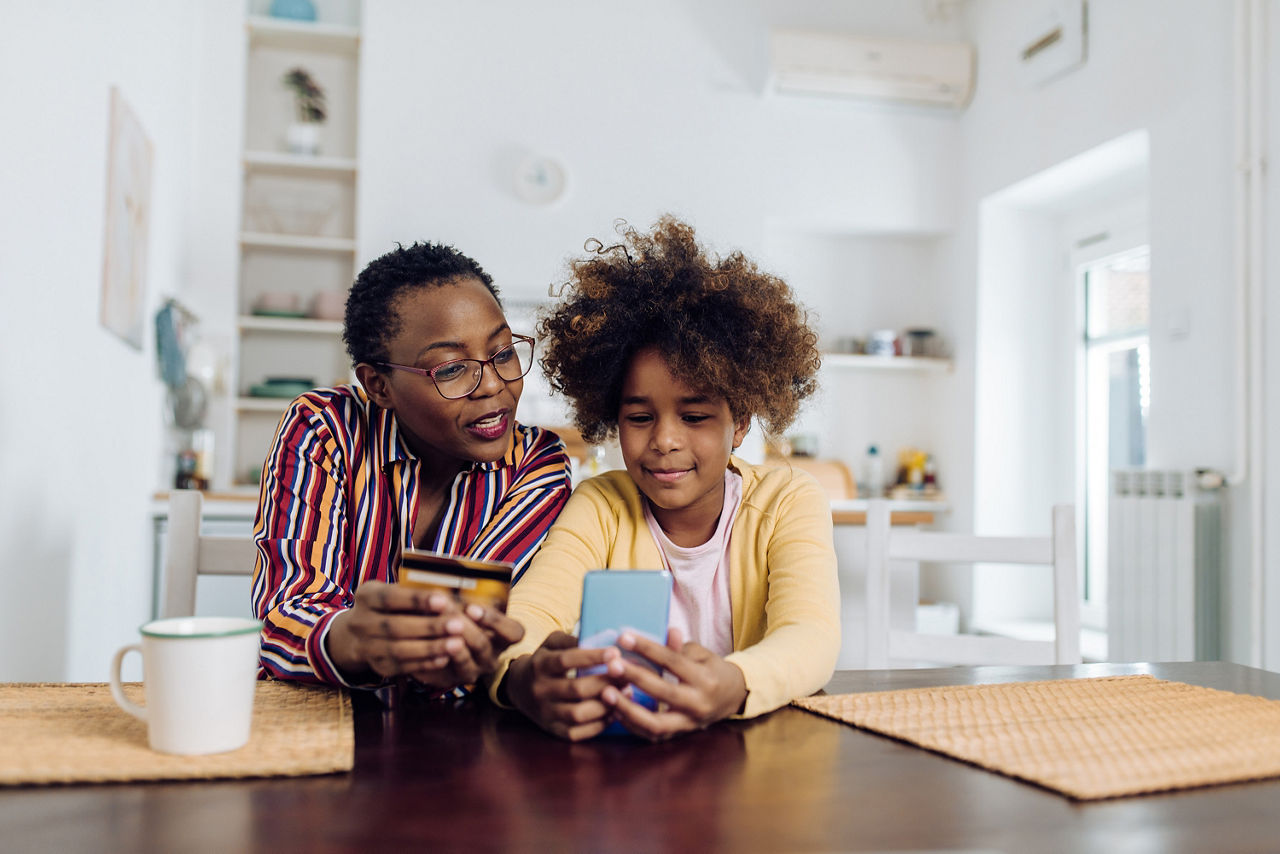 Ein Kind und dessen Mutter eröffnen ein Taschengeldkonto mit dem Smartphone.