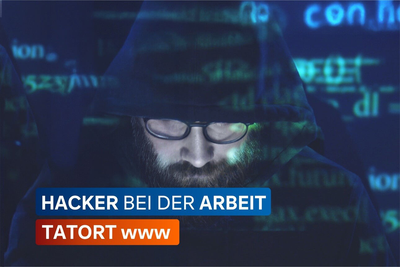 Mann mit Kapuzenpullover und Brille vor einem Bildschirm mit grünem Code.