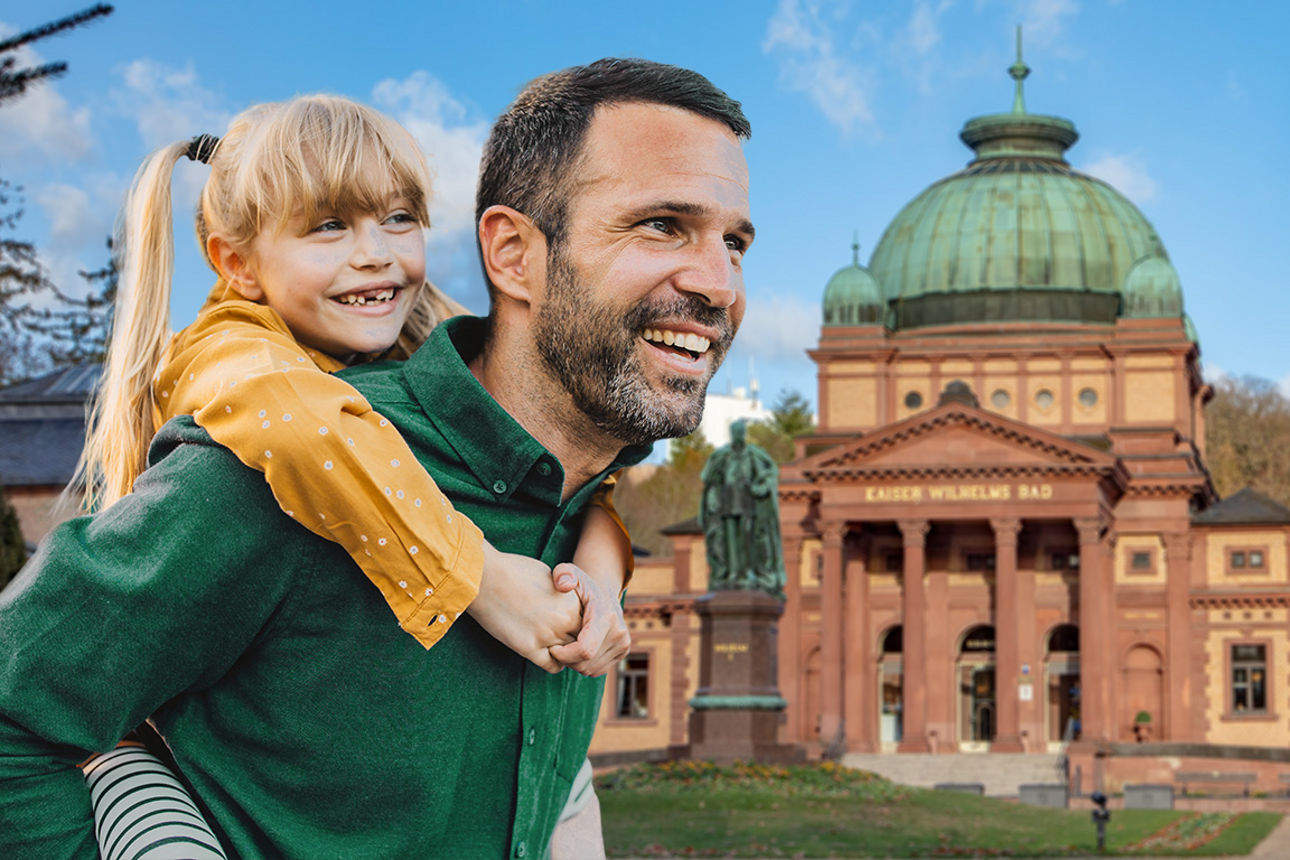 Lächelnder Vater trägt seine Tochter auf dem Rücken vor einem Rathaus