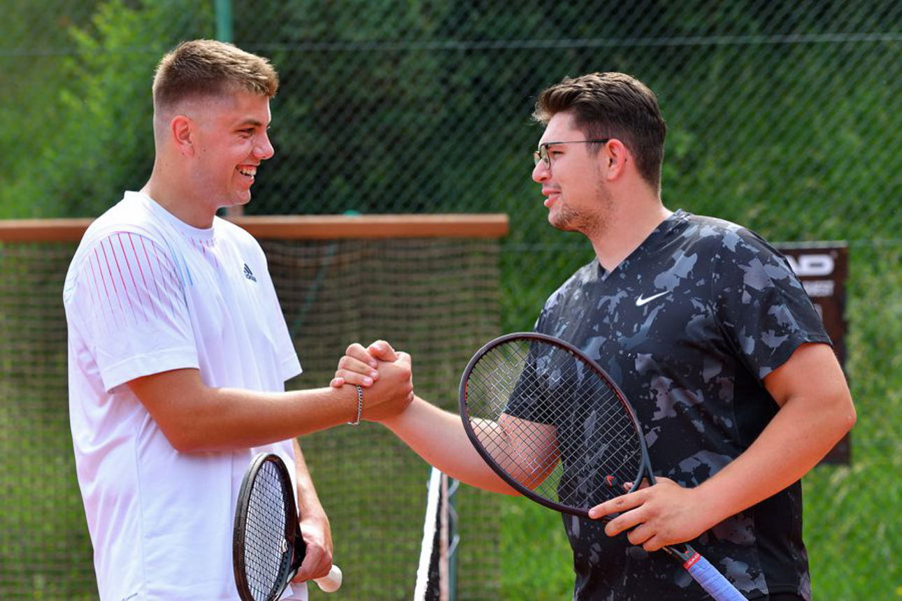 Junge Männer geben sich die Hand beim Tennisspielen
