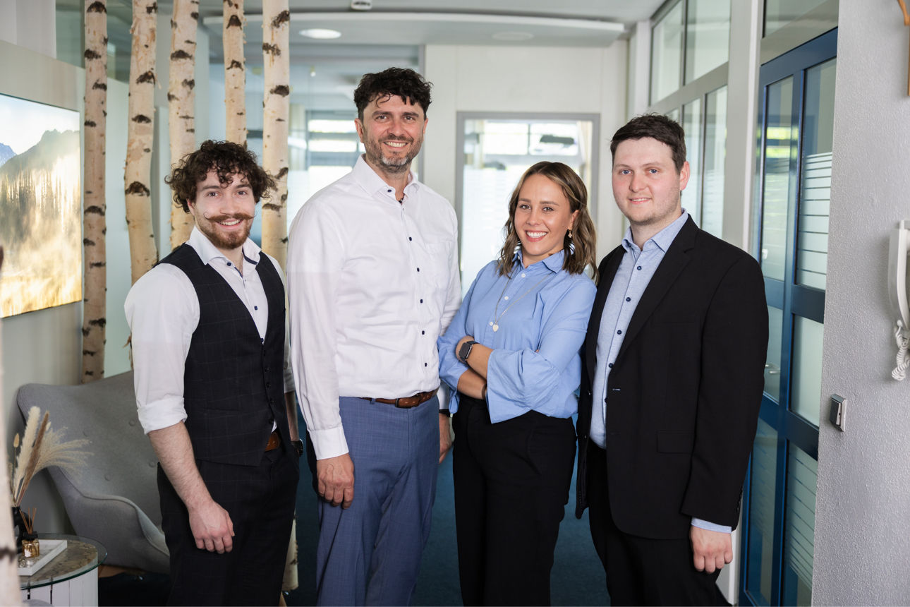 drei Männer und eine Frau stehen in einem Büro