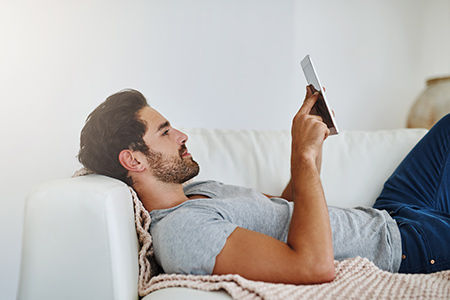 Mann auf dem Sofa mit einem Handy in der Hand