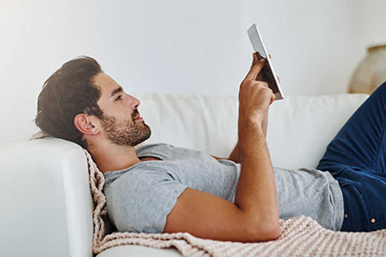 Mann auf dem Sofa mit einem Handy in der Hand