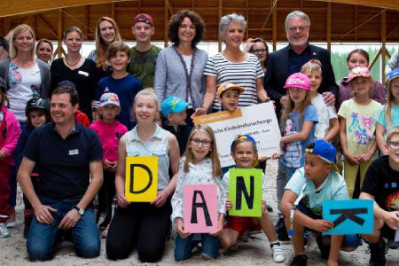 Gruppe von Kindern und Erwachsenen lachen in die Kamera