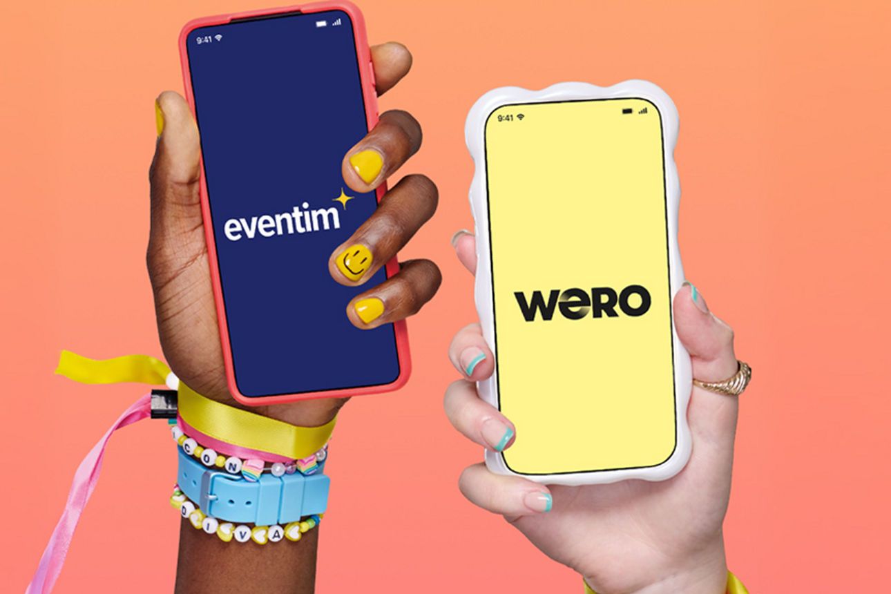 Zwei junge Hände mit bunten Armbändern strecken ihre Smartphones mit Wero und Eventim in die Kamera