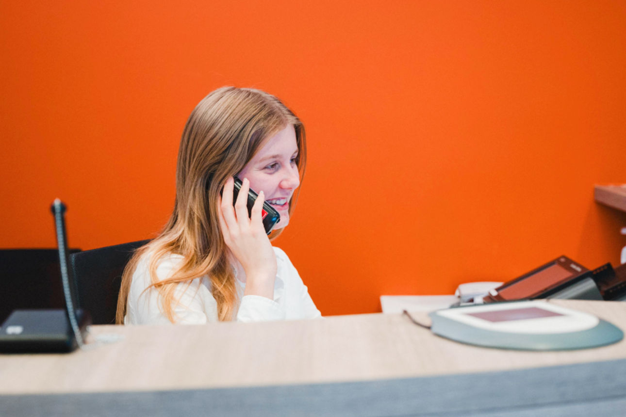 Junge Beraterin im Empfangbereich am Telefon