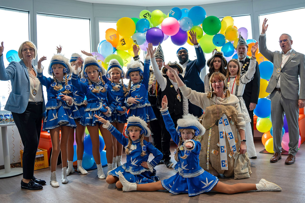 Kinder in bunten Kostümen feiern fröhlich mit Luftballons und Konfetti.