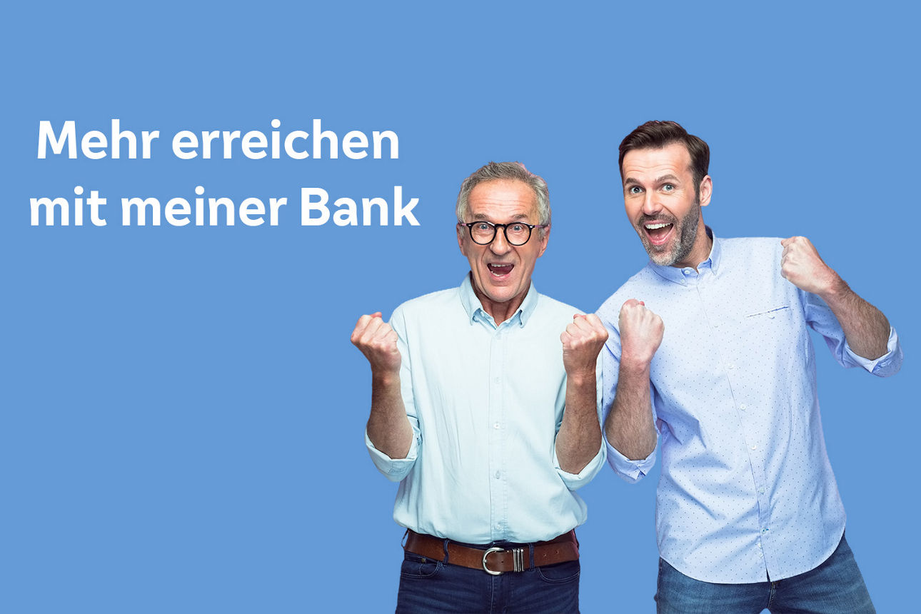 Zwei Männer stehen vor einer blauen Wand mit dem Schriftzug „Mehr erreichen mit meiner Bank.”
