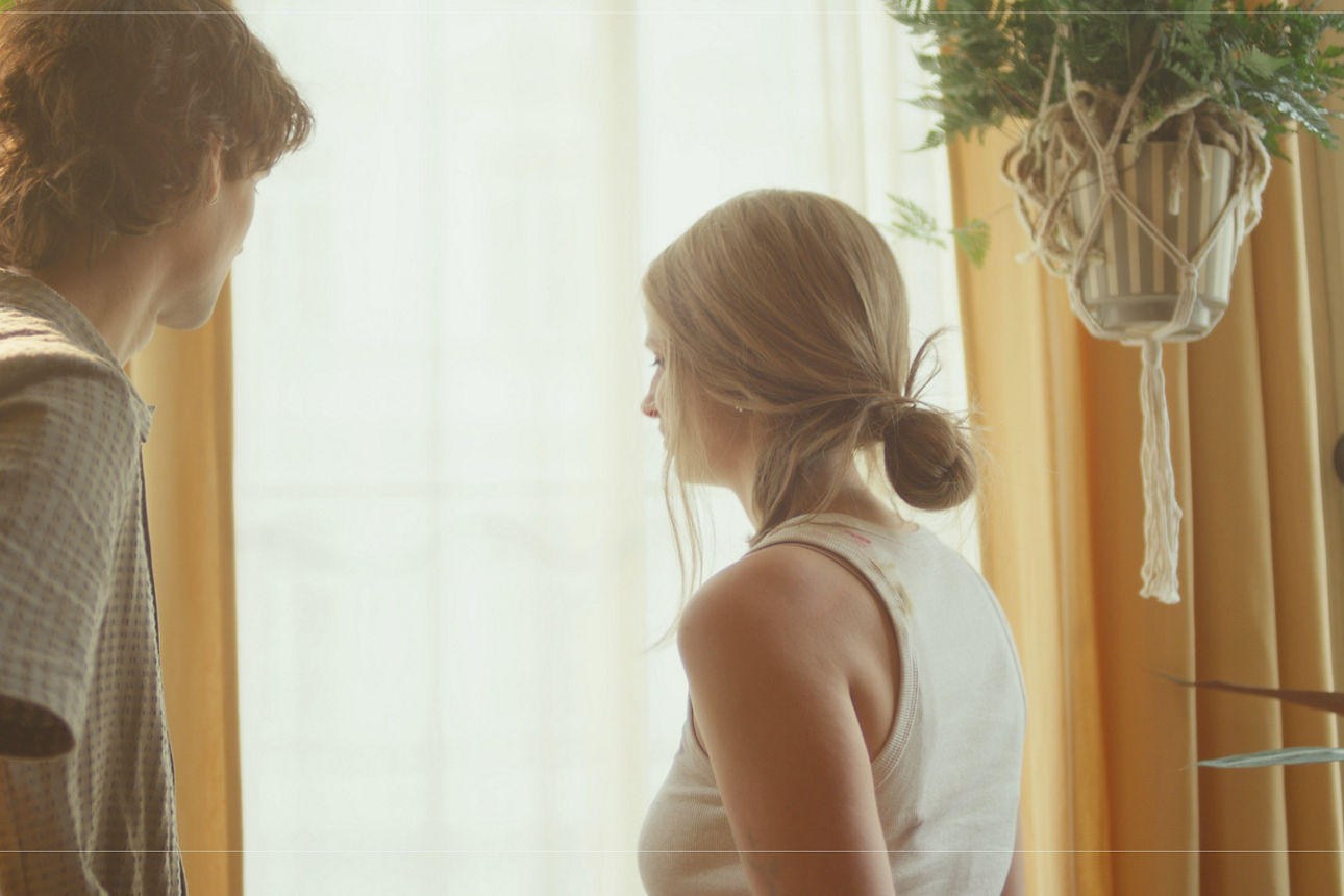 Ein Mann und eine Frau stehen mit dem Blick zum Fenster in einer hell erleuchteten Wohnung. Ein Mann und eine Frau stehen mit dem Blick zum Fenster in einer hell erleuchteten Wohnung.