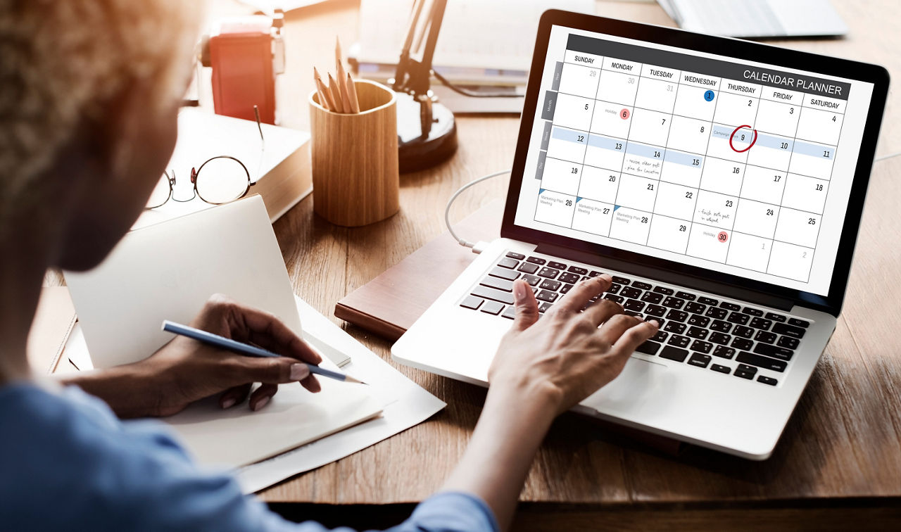 Person schaut in den digitalen Kalender am Laptop
