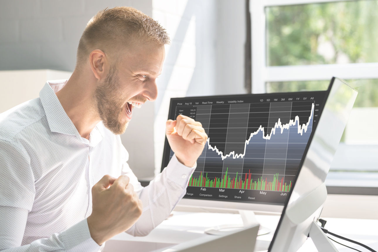 Junger Erwachsener jubelt vor einem Monitor