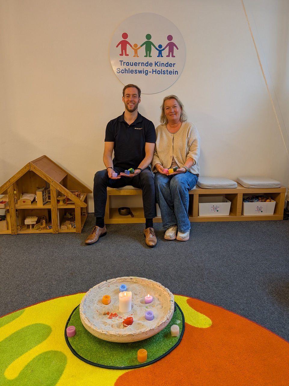 zwei Erwachsende sitzen in einem Spielraum für Kinder