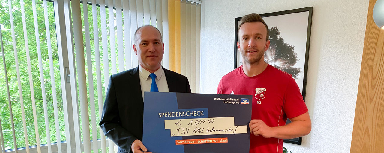Alexander Rauschert, Kundenberater der Raiffeisen-Volksbank Haßberge eG übergibt einen Spendenscheck an den TSV Goßmannsdorf