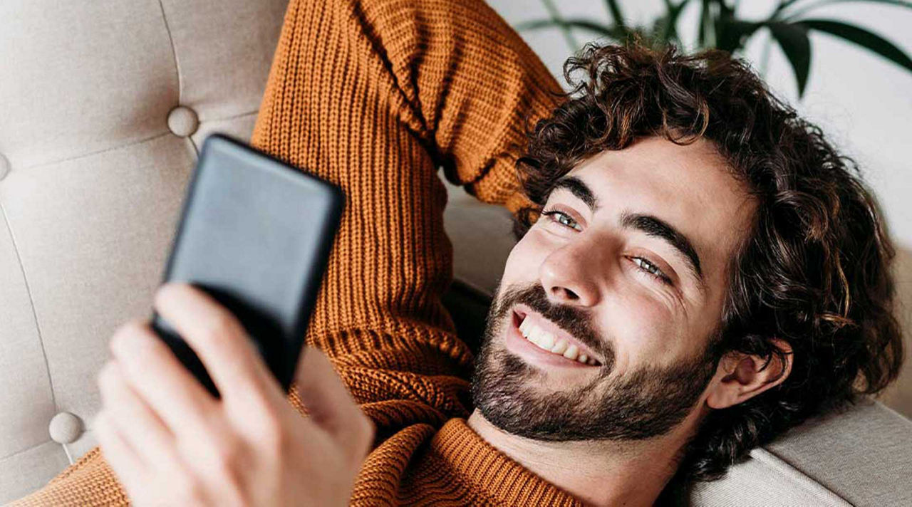 Know-How für Ihr Vermögen - Mann schaut im Liegen auf sein Handy