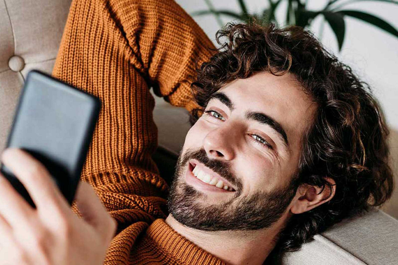 Know-How für Ihr Vermögen - Mann schaut im Liegen auf sein Handy