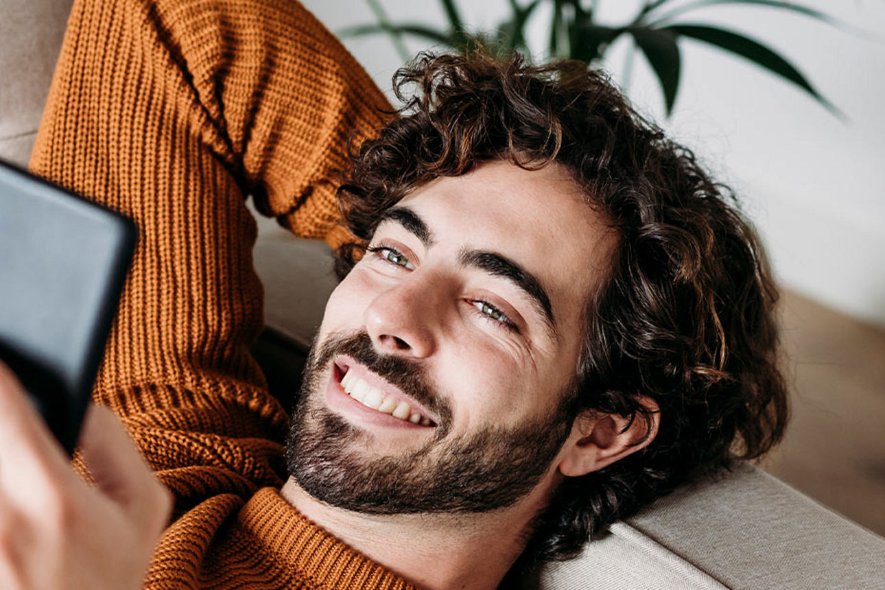 Ein Mops mi Ananashut auf dem Kopf blickt in die Kamera.