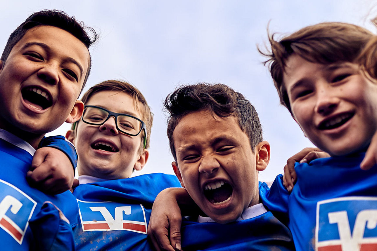 Lachende Gruppe von Kindern in Volksbank-Trikots