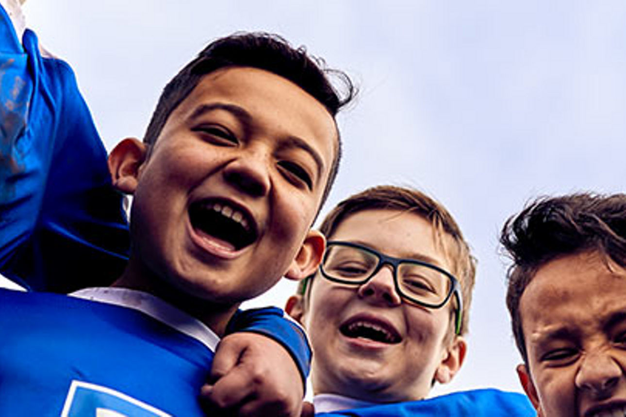 Eine Kinder-Fußballmannschaft in Volksbank-Trikots feiert einen Torschützen