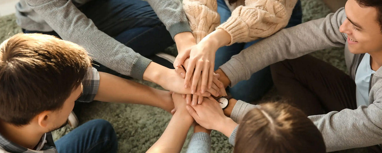 Gruppe die im Kreis die Hände sammeln als Teambuilding