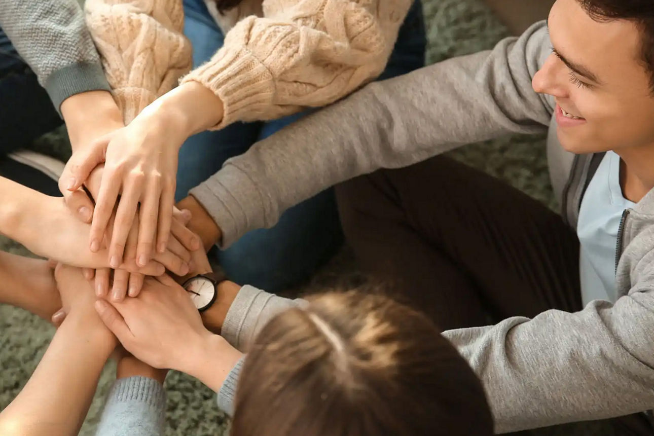 Gruppe die im Kreis die Hände sammeln als Teambuilding